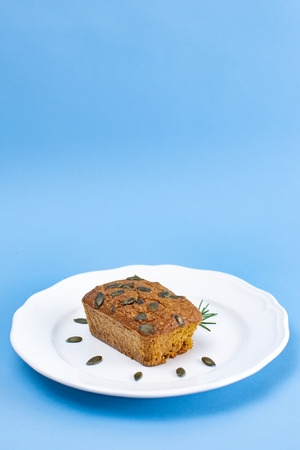 Gluten-Free pumpkin bread with pumpkin seed in white plate set on light blue background.の写真素材