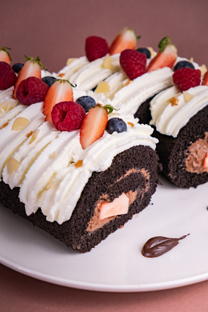 Chocolate roll cake with berries and fresh cream.の写真素材