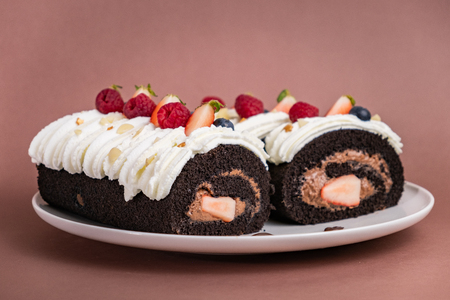 Chocolate roll cake with berries and fresh cream.の写真素材