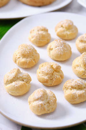choux cream or cream puff or French profiteroles with fresh cream set on cafe table.の写真素材