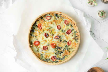 Homemade cheesy spinach quiche for brunch. set on white cafe table background.の写真素材
