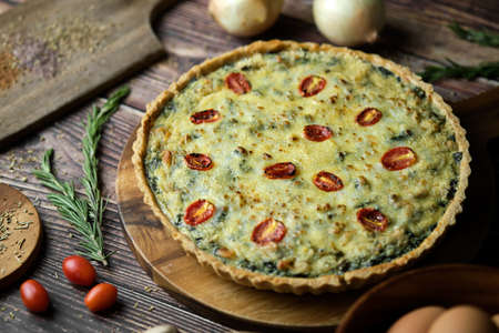 Homemade cheesy spinach quiche for brunch. set on wooden cafe table background.の写真素材