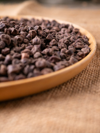Raw Dark Brown Chickpeas (Kala Chana) on a rustic wooden table. Dry Black chickpea (ceci neri) background close up.の写真素材