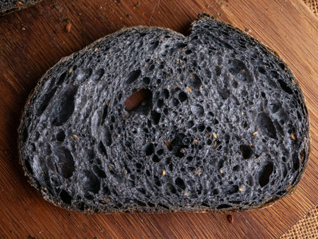 Fresh baked black charcoal sourdough ciabatta bread sliced on wooden boardの写真素材