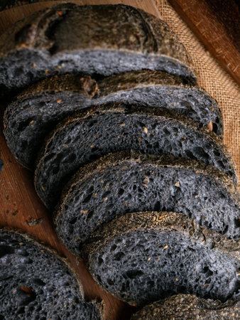 Fresh baked black charcoal sourdough ciabatta bread sliced on wooden board