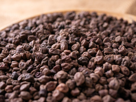 Raw Dark Brown Chickpeas (Kala Chana) on a rustic wooden table. Dry Balck chickpea (ceci neri) background close up.の写真素材