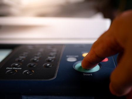 Close up hand office man press start button on panel to using the Office professional multi-function printer scanner for scanning document printing. a Copy machinesの写真素材