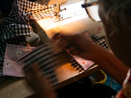 Senior Woman Working with Sewing Machine. Elderly Hands Creating Garments through Skilled Labor