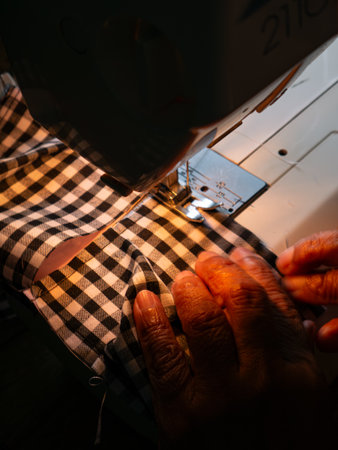 Senior Woman Working with Sewing Machine. Elderly Hands Creating Garments through Skilled Laborの写真素材