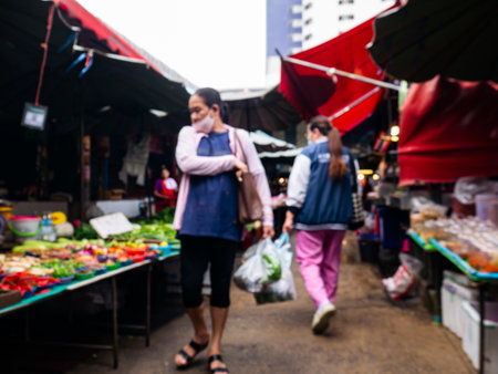 Blurred View of Shoppers at Local Market with Fresh Vegetables Stall.の写真素材