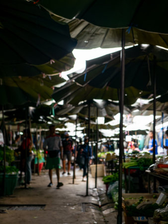 Blurred View of Shoppers at Local Market with Fresh Vegetables Stall.の写真素材