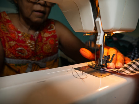 Elderly Womanâ€™s Hands Sewing Fabric with Electric Sewing Machine. Senior Labor and Handicraft...