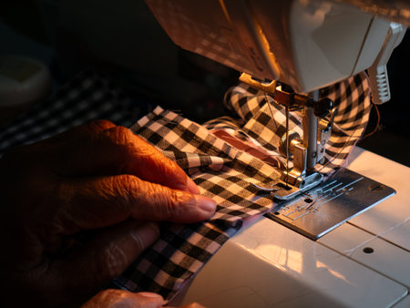 Senior Woman Working with Sewing Machine. Elderly Hands Creating Garments through Skilled Laborの写真素材