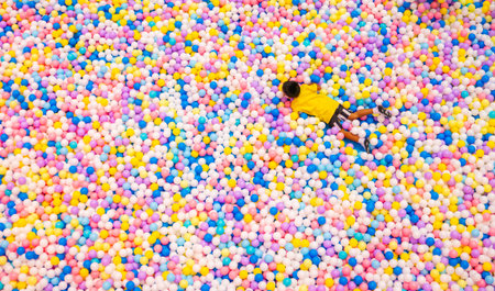 Child playing in colorful ball pit with thousands of multicolored plastic balls at indoor playground entertainment centerの写真素材