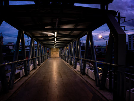Covered Pedestrian Bridge at Twilight - Urban Walkway with Motion Blur and Evening Skyの写真素材