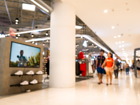Blurred Couple Walking Hand in Hand Through Modern Shopping Mall with Shopping Bagsの写真素材