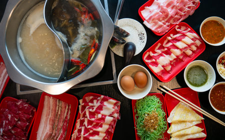 Hotpot Shabu Sukiyaki Set with Sliced Meat, Noodles, and Dumplings on Restaurant Tableの写真素材