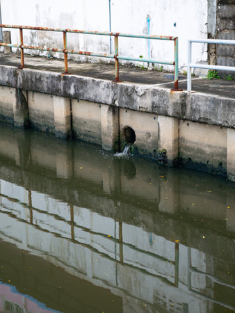 Polluted urban canal with sewage discharge pipe and contaminated water - Environmental pollution and...