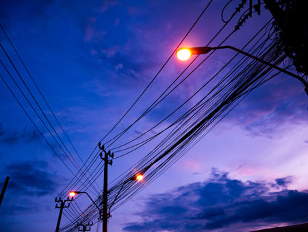 Beautiful Purple and Blue Twilight Sky with Electric Power Lines and Street Lights Creating Dramatic Urban Silhouetteの写真素材