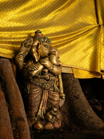 Bronze Ganesha Statue with Golden Cloth at Hindu Temple - Elephant God Holding Musical Instrumentの写真素材