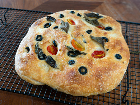 Freshly Baked Focaccia Bread with Olives and Tomatoes Cooling on Wire Rack - Golden Italian Flatbread Close-Upの写真素材