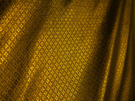 Abstract Golden Mesh Fabric Texture with Flowing Folds - Luxurious Shimmering Material Backgroundの写真素材