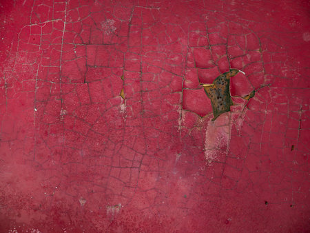 Deep scratch and peeling paint damage on red car body panel near wheel well showing primer and rustの写真素材