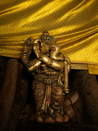 Bronze Ganesha Statue with Golden Cloth at Hindu Temple - Elephant God Holding Musical Instrumentの写真素材