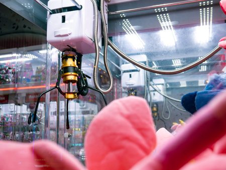 Golden Yellow Claw Grabber Mechanism Inside Arcade Crane Machine with Pink Plush Toys and LED Lights