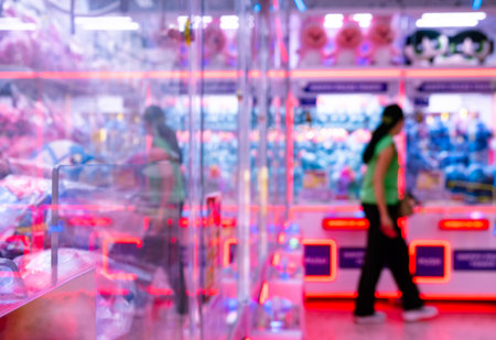 Blurred Motion of People Walking Past Colorful Neon Arcade Game Machines with Red and Blue LED Lightsの写真素材