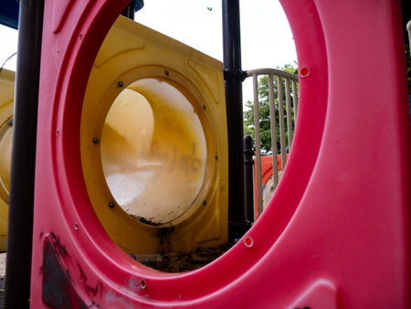 Abandoned Old Playground Equipment Viewed Through Red Frame - Neglected Children's Play Area with Overgrown Treesの写真素材