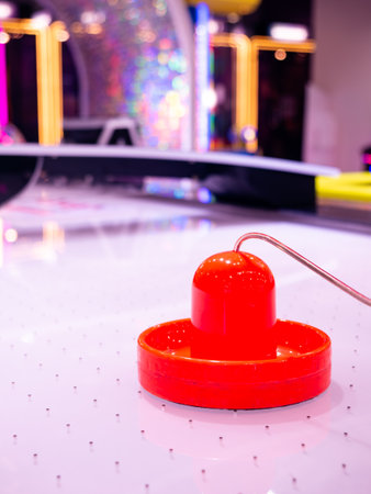 Red Air Hockey Puck and Mallet on White Gaming Table in Colorful Arcade Entertainment Centerの写真素材