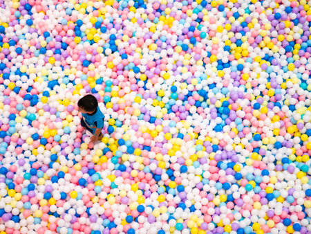 Child playing in colorful ball pit with thousands of multicolored plastic balls at indoor playground entertainment centerの写真素材