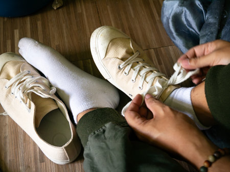 Top view of person wearing beige canvas sneakers with white socks relaxing on wooden floor at homeの写真素材
