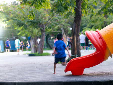 Blurred out of focus colorful children playground with slides and climbing equipment in public park surrounded by treesの写真素材