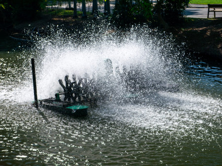 Dramatic water fountain spray creating large splash explosion with droplets in urban park pond...