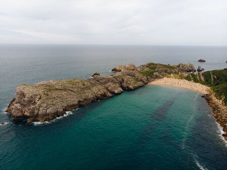 Aerial shot of beautiful spanish beach with turquoise water and rocky cliffsの写真素材