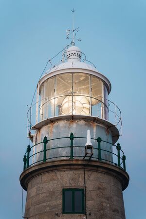 Close up of lighthouse beacon lighting up at sunset and blue backgroundの写真素材