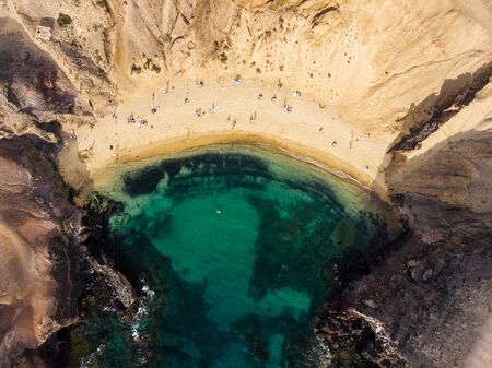 Aerial shot of village in Famara, Canary islands with ocean waves and beach at sunsetの写真素材