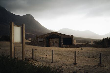 Abandoned church in cofete beach, Fuerteventura, Spain with rocky mountains in the background