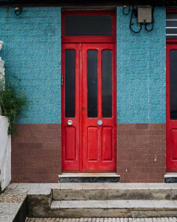 Red wooden door in old building with blue and brown tilesの写真素材
