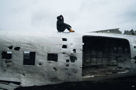 Famous plane wreck in Iceland with black sand and a man standing on top