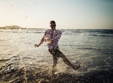 Young man splashing water on beautiful beach at sunset in Lanzarote, Spainの写真素材
