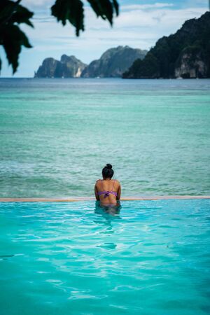 Young woman relaxing in infinity pool looking at beautiful islands in Koh Phi Phi, Thailandの写真素材