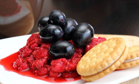 dessert of raspberry and grapes on a white plateの写真素材