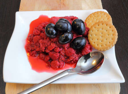 raspberry with grapes and biscuits served on a white plateの写真素材