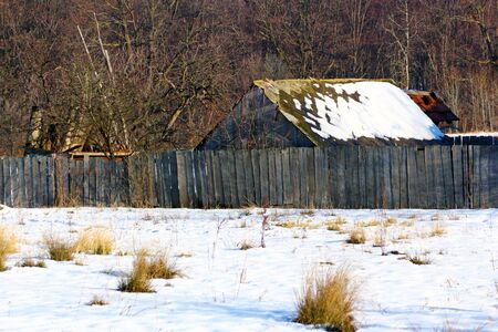 abandoned old farm covered in snow in a winter dayの写真素材