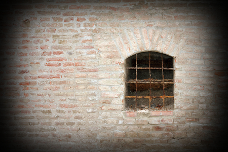 detail of a medieval window on abandoned building exterior brick wallの写真素材