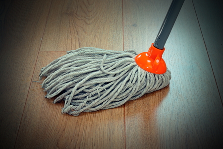 detail of wooden floor cleaning with orange mopの写真素材
