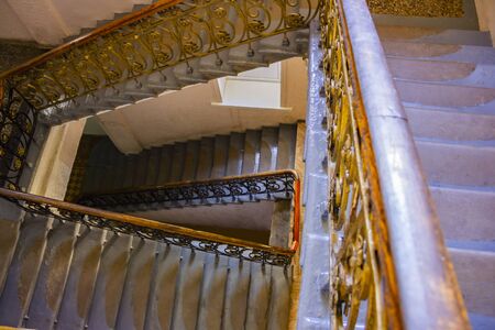 An old stairs with gold metal banister in empty building.の写真素材